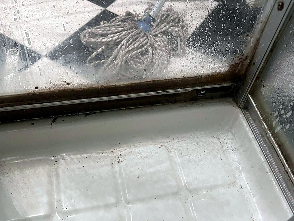 Douchecabine voor de schoonmaak, zwarte randen langs de rails
